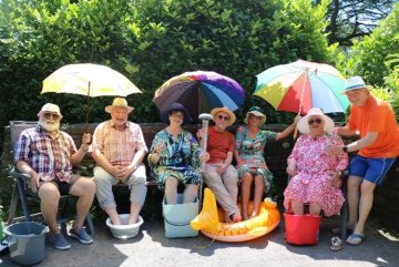 Seniorinnen und Senioren sitzen in der Sonne.