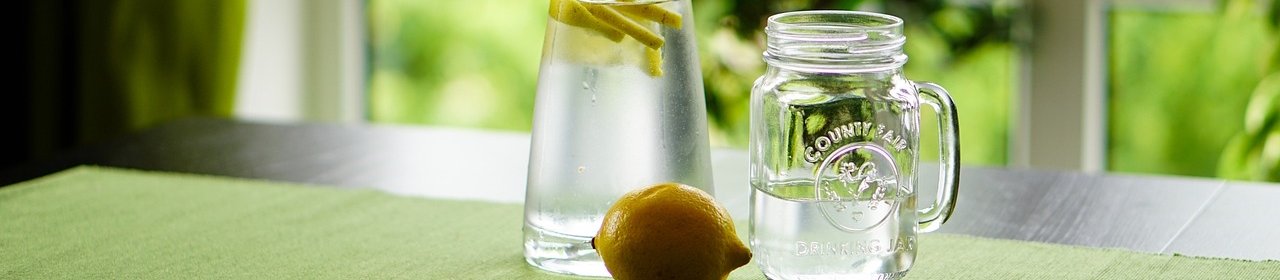 Eine Flasche mit Zitronenwasser vor einem Fenster.