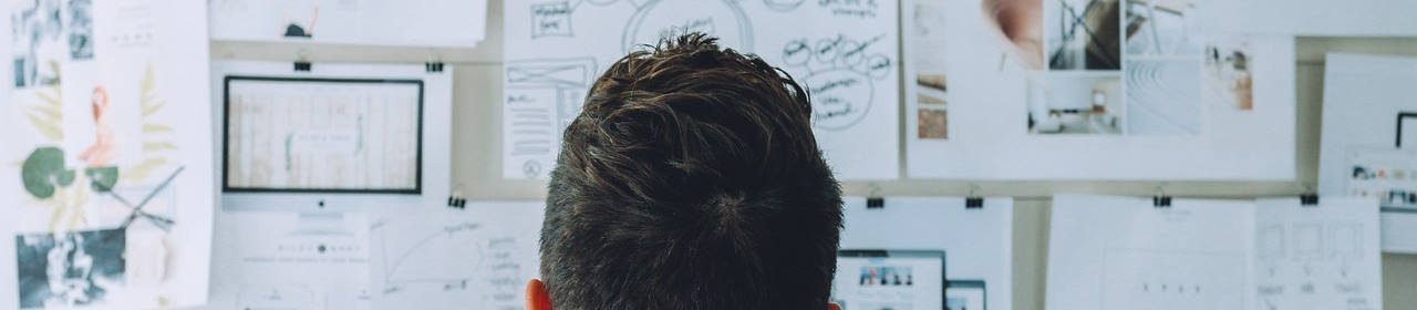 Ansicht einer Frau von hinten mit Blick auf eine große Pinwand (Titelbild) Ansicht einer Frau von hinten mit Blick auf eine große Pinwand (Titelbild)